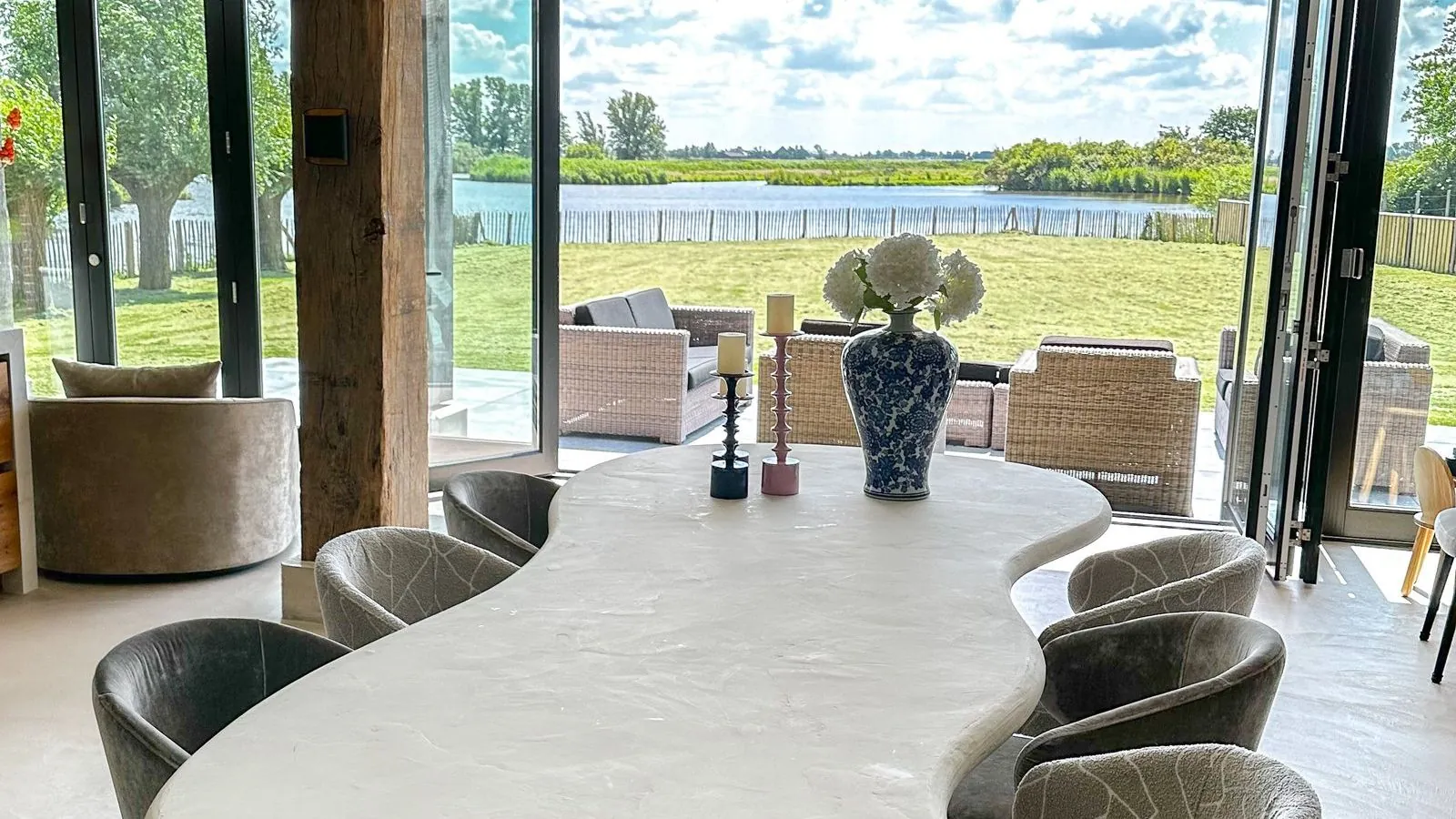 Eetkamer met grote glazen pui en uitzicht op het weiland achter de woning