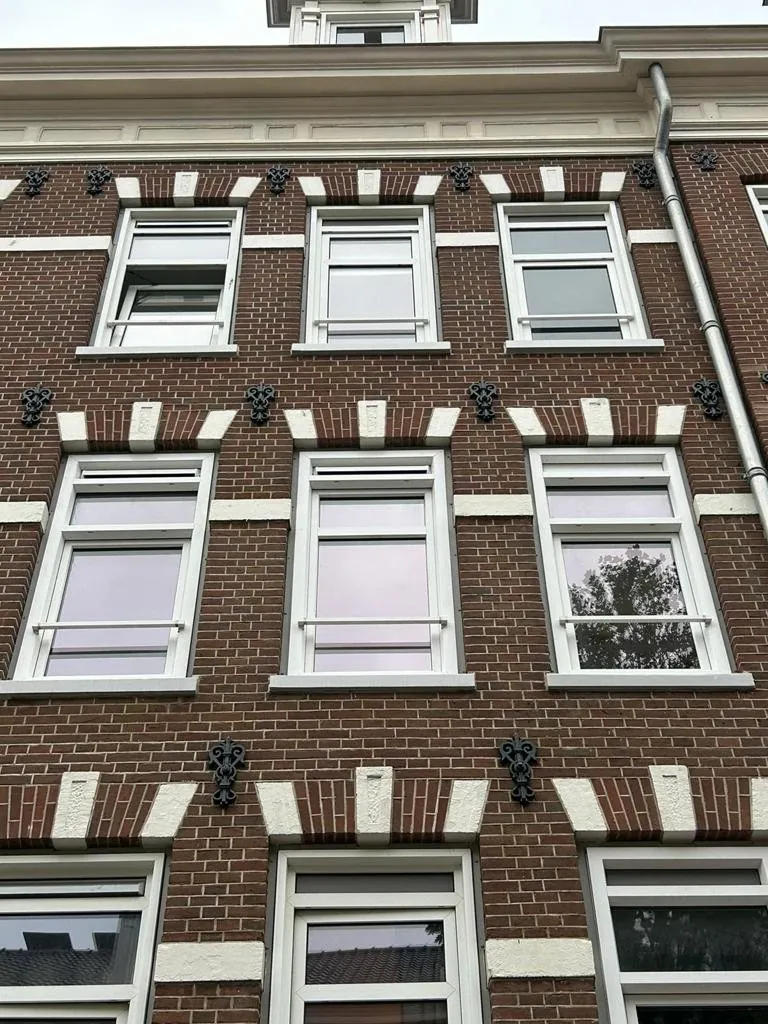 Bakstenen gevel met nieuwe witte kozijnen over drie verdiepingen