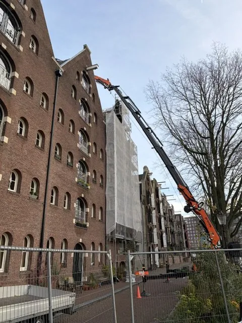Autolaadkraan bij een pand aan de gracht tijdens een project
