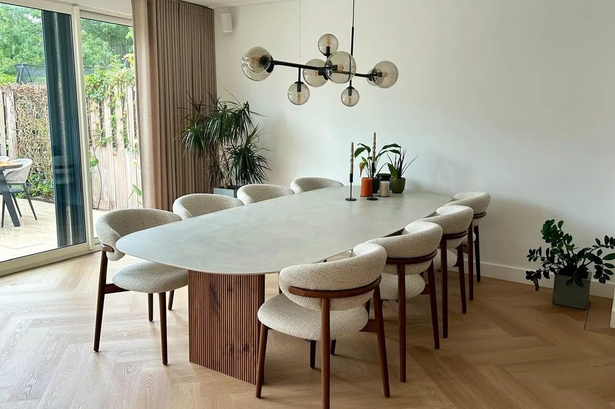 Woonkamer met schuifpui naar de tuin, ovale eettafel en visgraatvloer